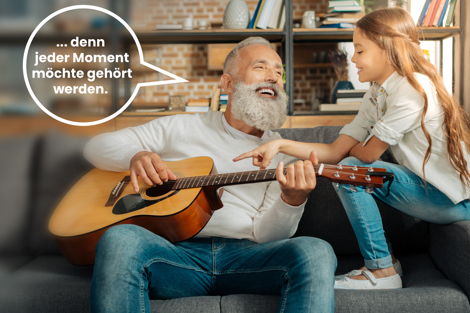 Jeder Moment möchte gehört werden. Ein älterer Herr spielt für ein Kind, vermutlich die Enkelin Gitarre. Wenn das Gehör nachlässt helfen Hörgeräte